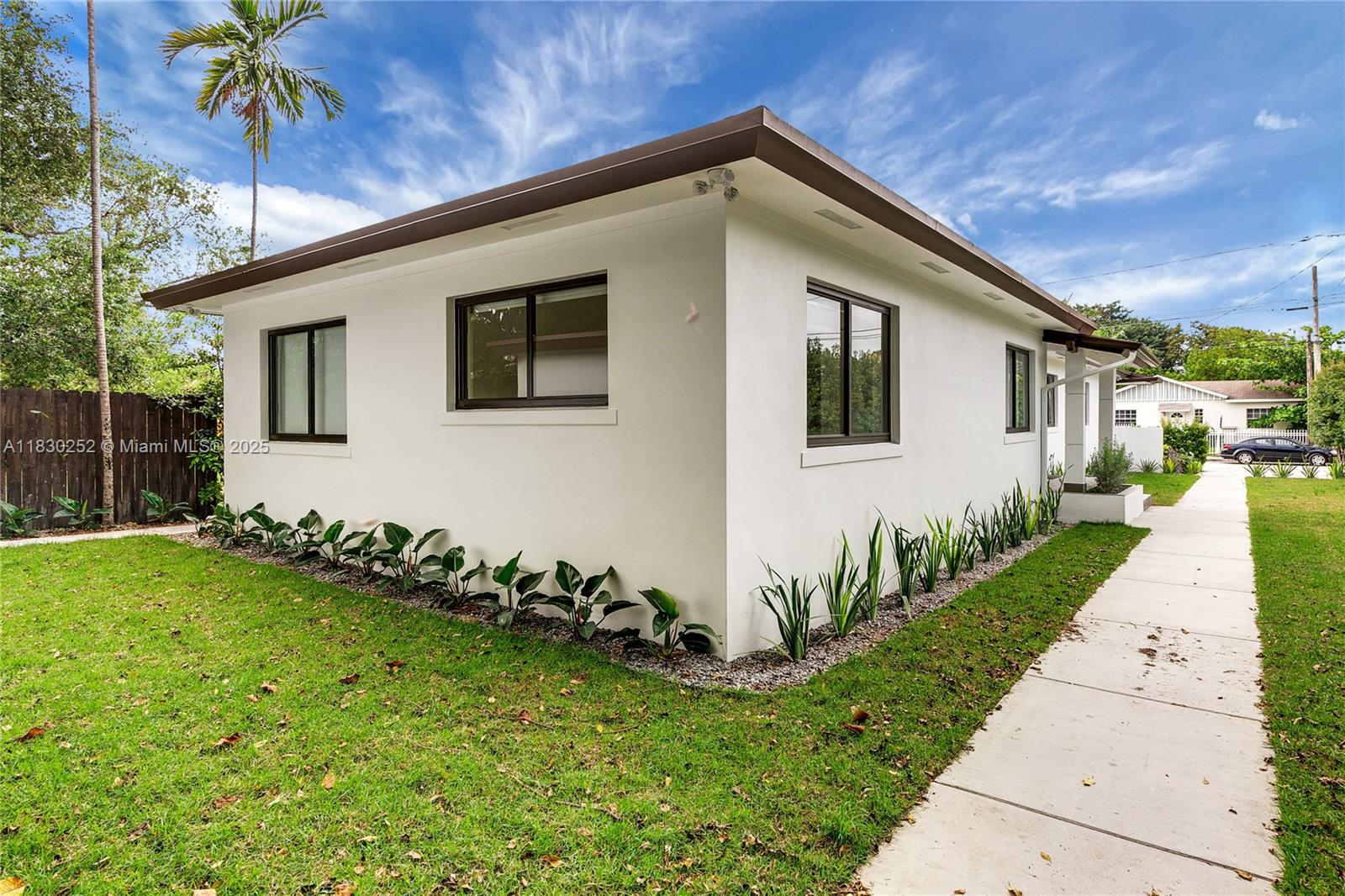 A white single-story house with dark-framed windows sits next to a concrete walkway — 36 NW 52nd St, Miami FL 33127, MIAMI, FL