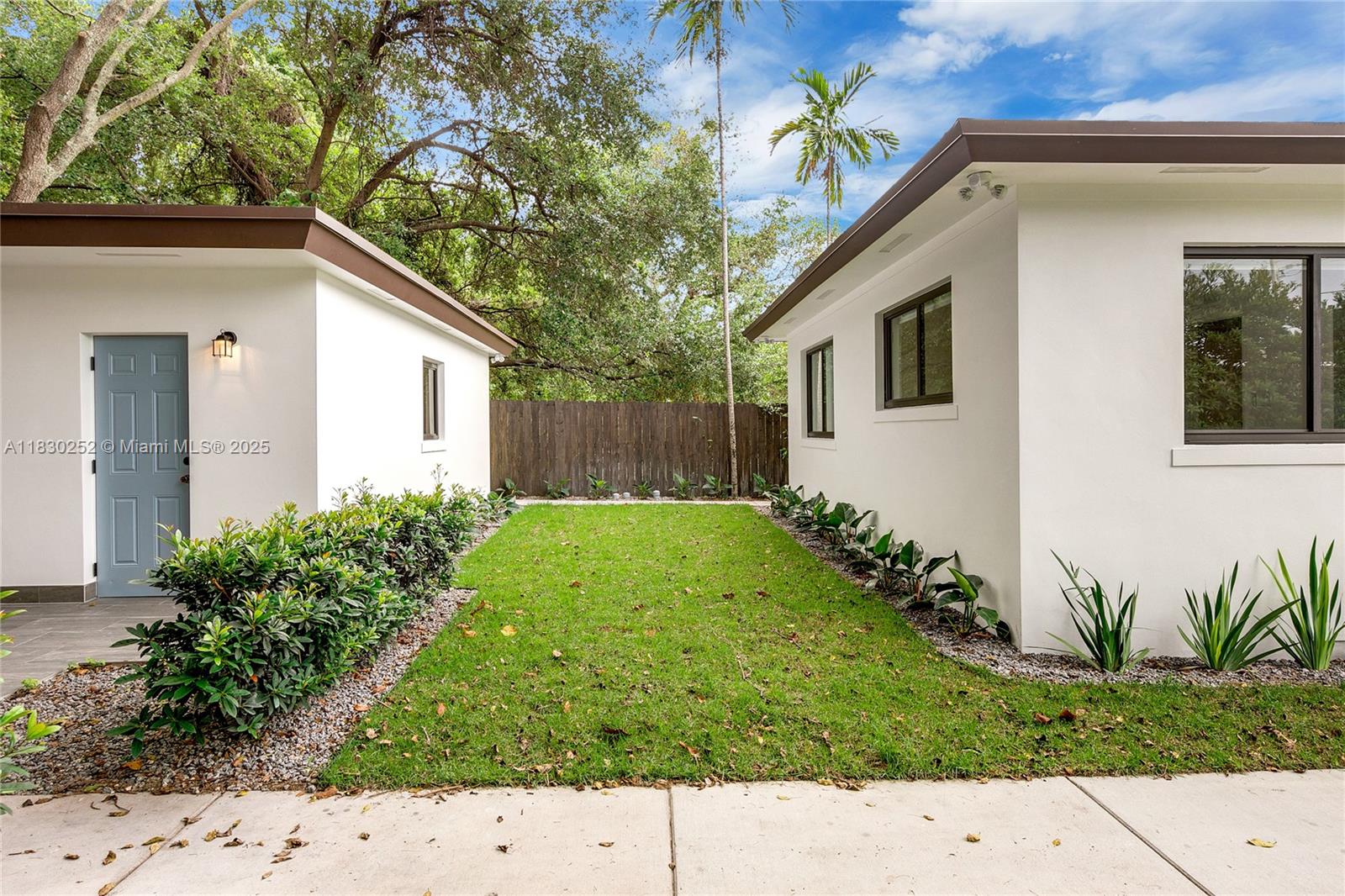 A grassy yard sits between two white exterior buildings with dark trim and landscaping — 36 NW 52nd St, Miami FL 33127, MIAMI, FL