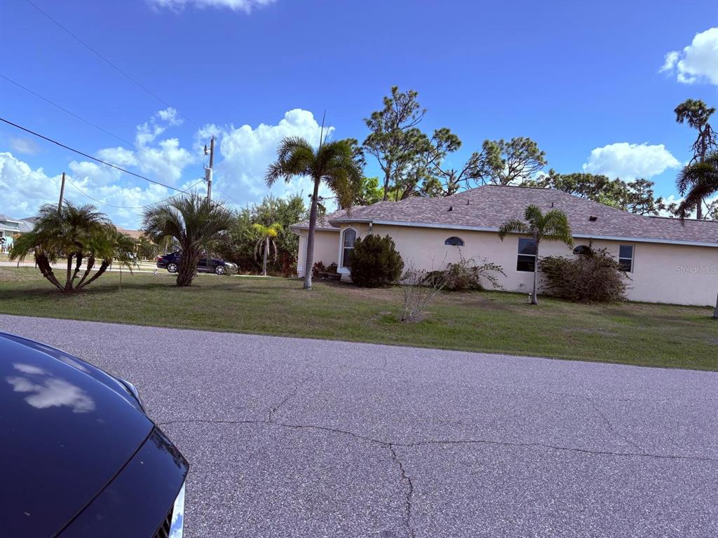A single-story house with a light-colored exterior sits behind a lawn with palm trees — 196 LINDA LEE DRIVE, ROTONDA WEST, FL