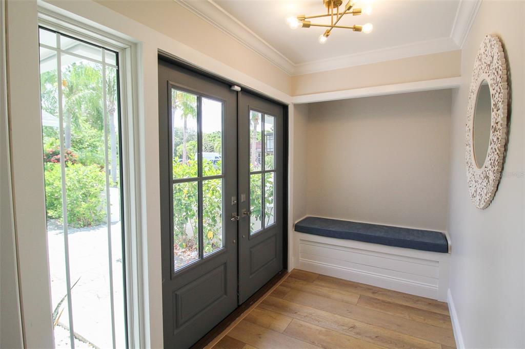 An entryway features a built-in bench, a round decorative mirror, and dark double glass doors — 691 RUSSELL STREET, LONGBOAT KEY, FL