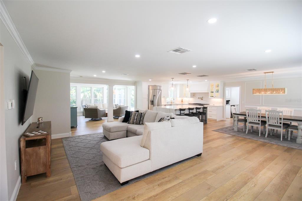An open-concept living room, dining area, and kitchen with light wood floors and white cabinetry — 691 RUSSELL STREET, LONGBOAT KEY, FL