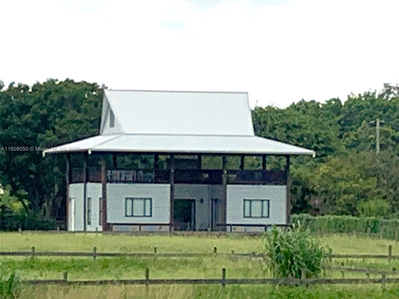 A two-story barn-style house with a metal roof stands in a grassy field — 22750 SW 154th ave, Miami FL 33170, MIAMI, FL