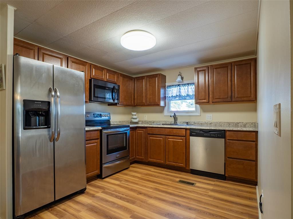 A kitchen features wood cabinets, stainless steel appliances, laminate countertops, and wood-look flooring — 401 DENICE DRIVE UNIT 401, SEMINOLE, FL