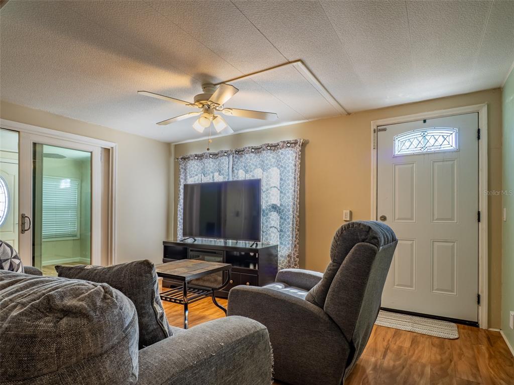 A living room features a ceiling fan, a television on a stand, and a recliner — 401 DENICE DRIVE UNIT 401, SEMINOLE, FL