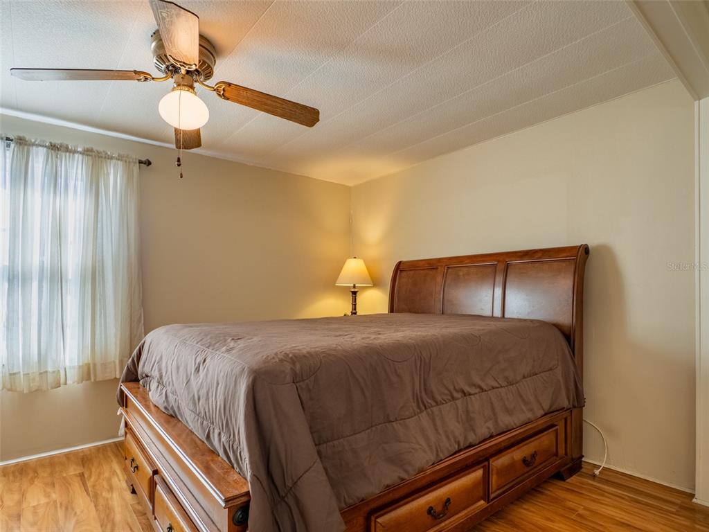 A bedroom features a wooden bed frame with storage drawers, wood-look flooring, and a ceiling fan — 401 DENICE DRIVE UNIT 401, SEMINOLE, FL