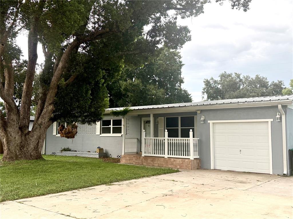 A single-story gray house features a white garage door, a front porch, and a large tree — 1731 BALDWIN DRIVE, ORLANDO, FL