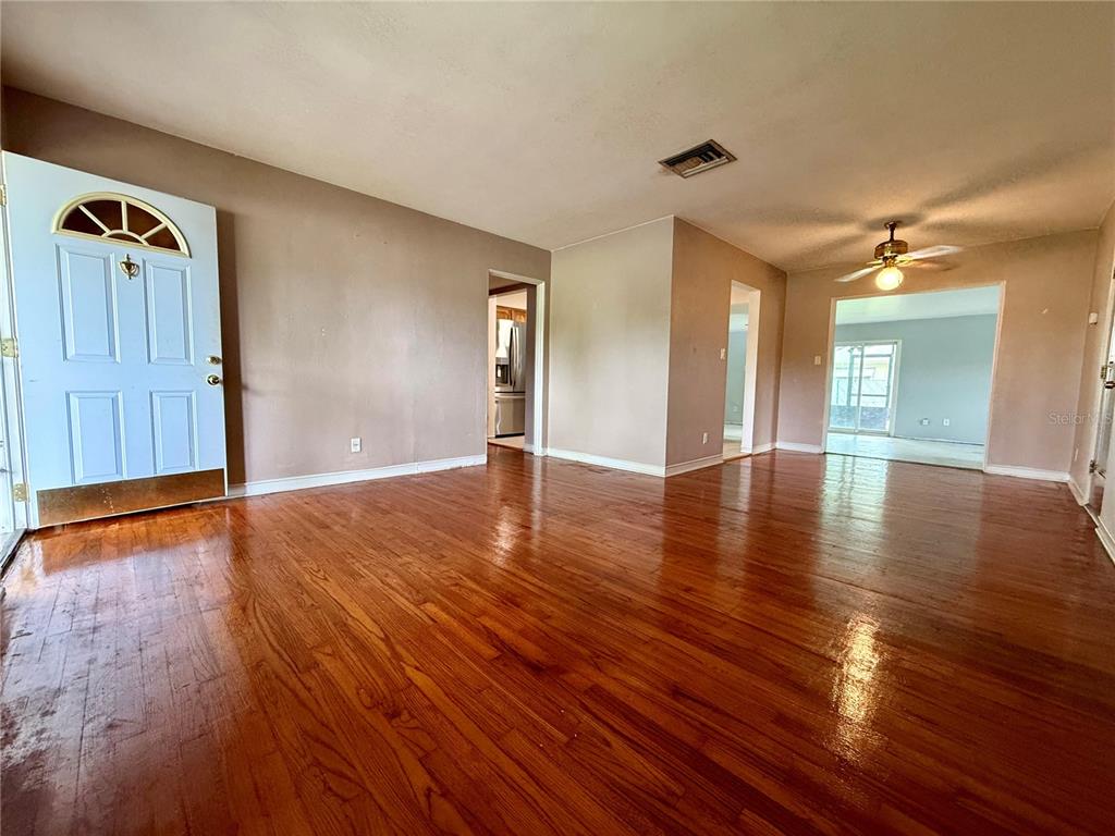 An interior view of a living room with hardwood floors, a white door, and ceiling fan — 1731 BALDWIN DRIVE, ORLANDO, FL