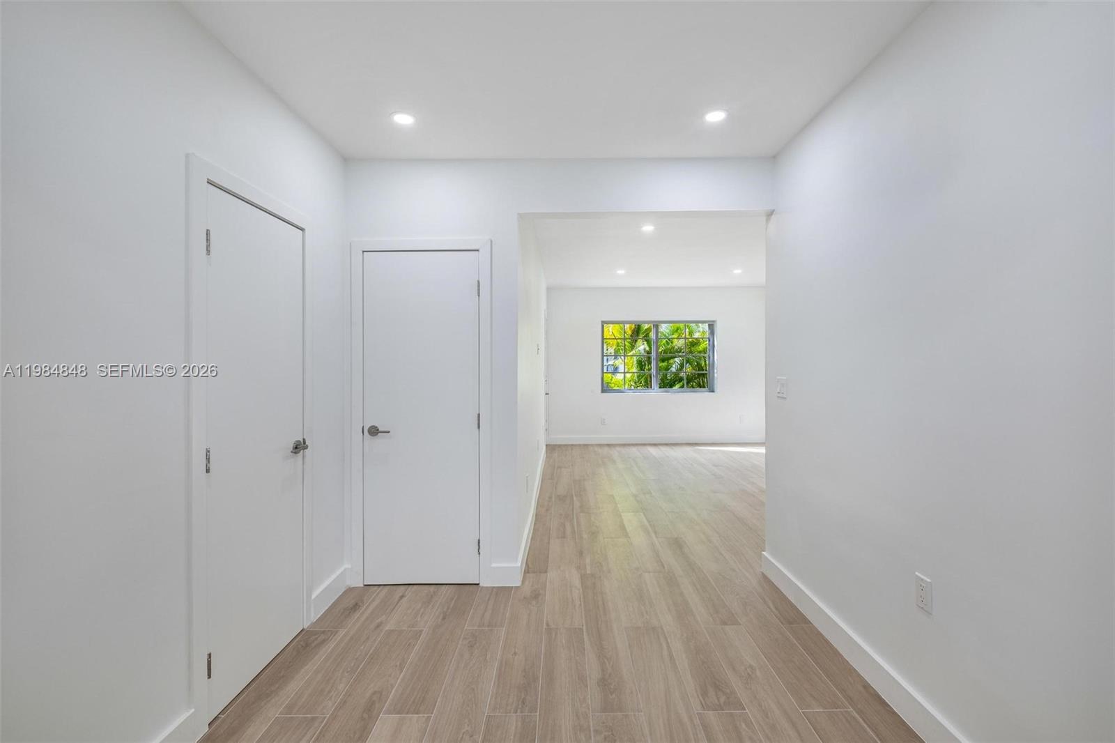 A bright hallway with light wood-look flooring leads to an open room with a window — 1610 Michigan Ave # 2, Miami Beach FL 33139, MIAMI BEACH, FL