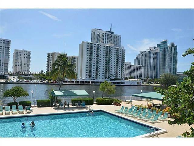 A swimming pool sits in front of a waterfront area with high-rise apartment buildings — 800 Parkview Dr # 1018, Hallandale Beach FL 33009, HALLANDALE BEACH, FL