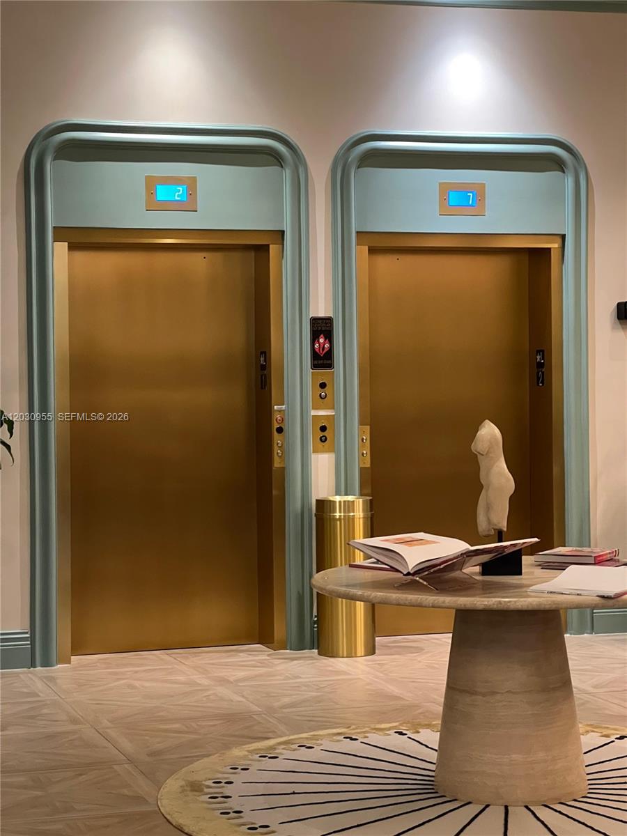 Two gold-toned elevator doors are set within a teal-trimmed wall in a modern lobby — 2700 NW 2nd Avenue # 325, Miami FL 33127, MIAMI, FL