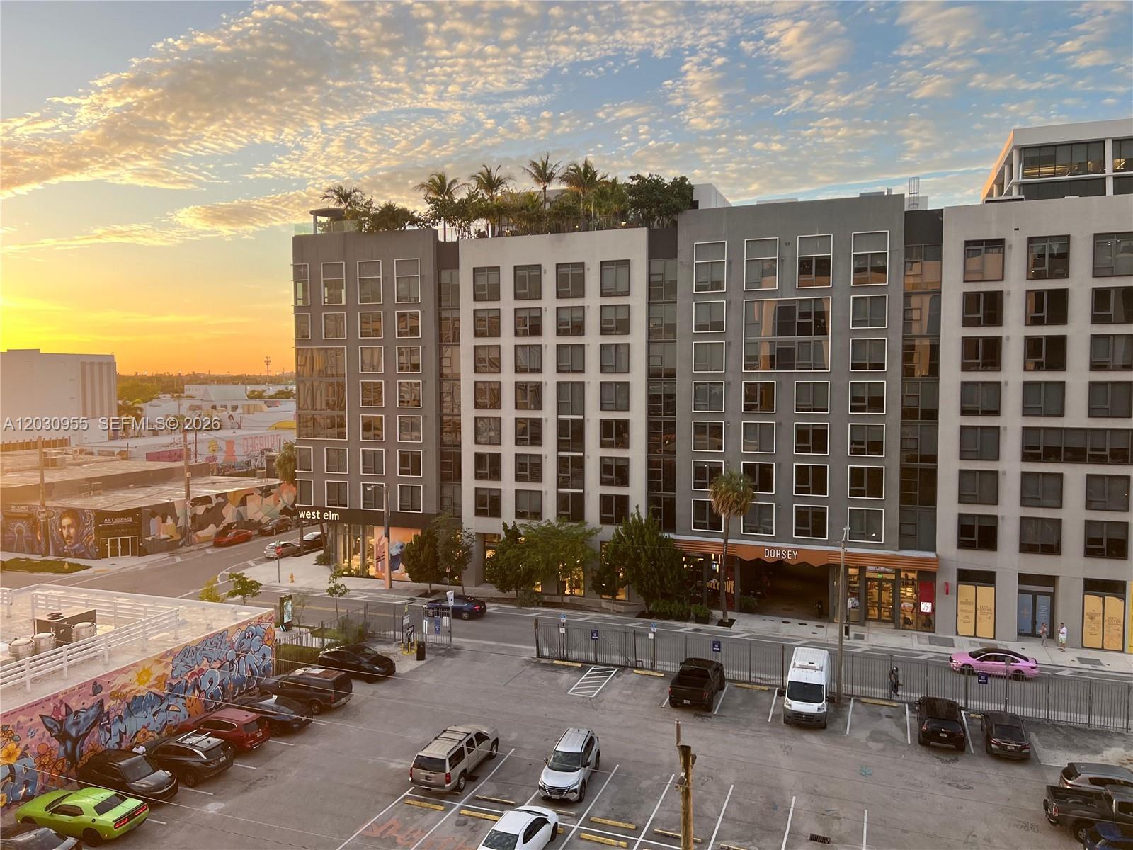An exterior view of a modern apartment building with a parking lot in the foreground — 2700 NW 2nd Avenue # 325, Miami FL 33127, MIAMI, FL