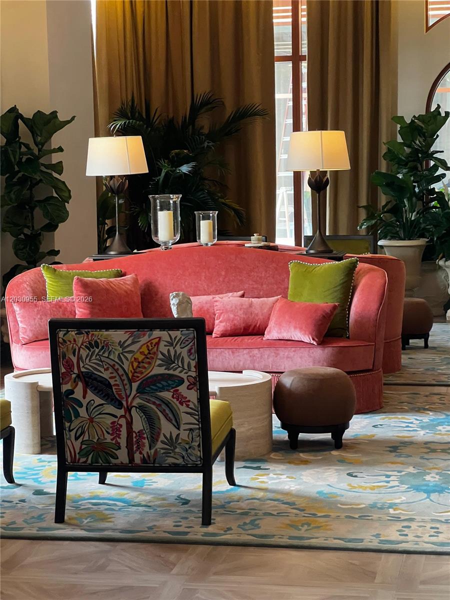 A living room features a curved pink sofa, patterned accent chair, and large potted plants — 2700 NW 2nd Avenue # 325, Miami FL 33127, MIAMI, FL