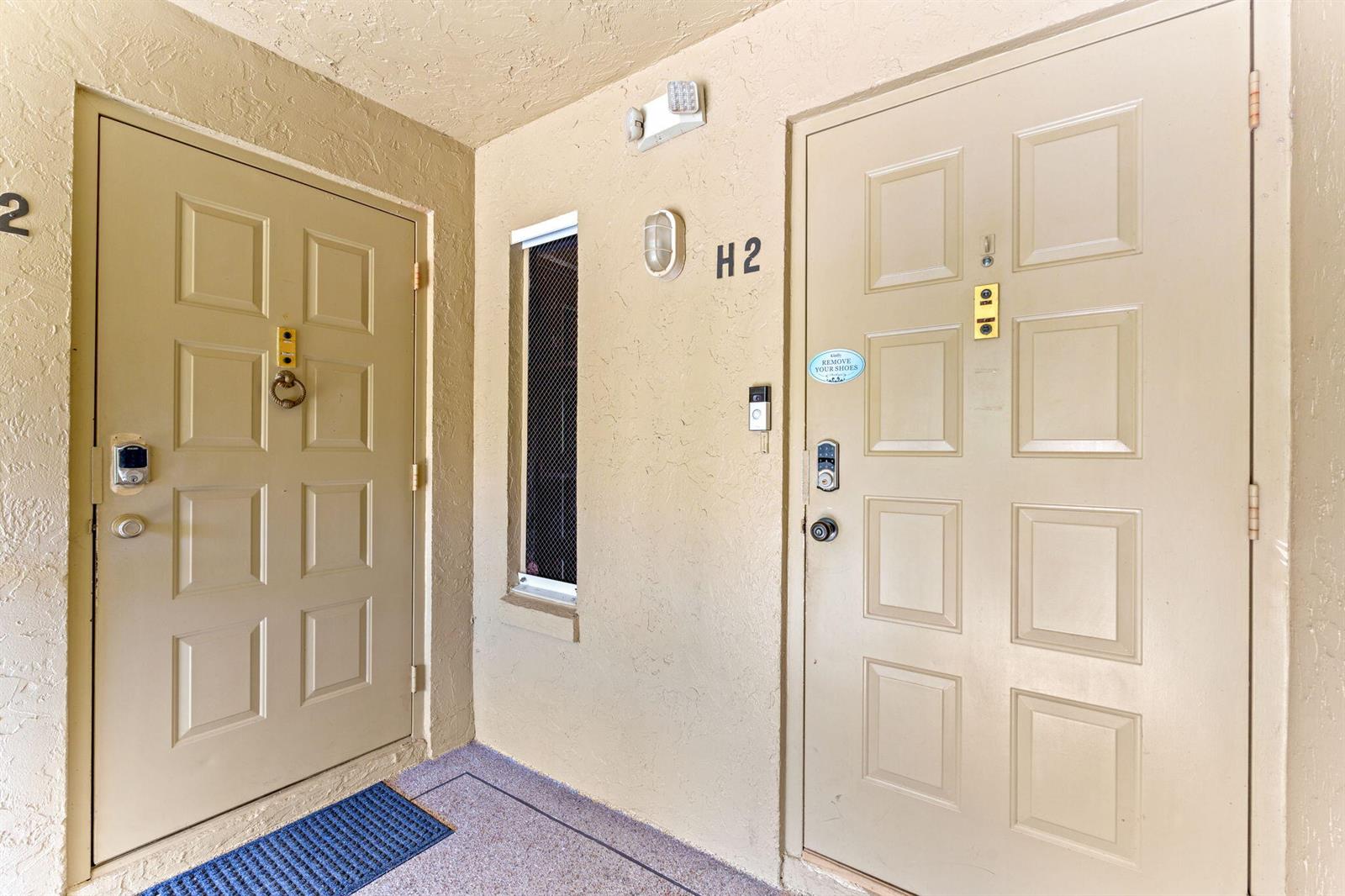 Two beige apartment doors with smart locks and a small window are in an entryway — 723 Sunny Pine Way # H2, FL 33415, FL