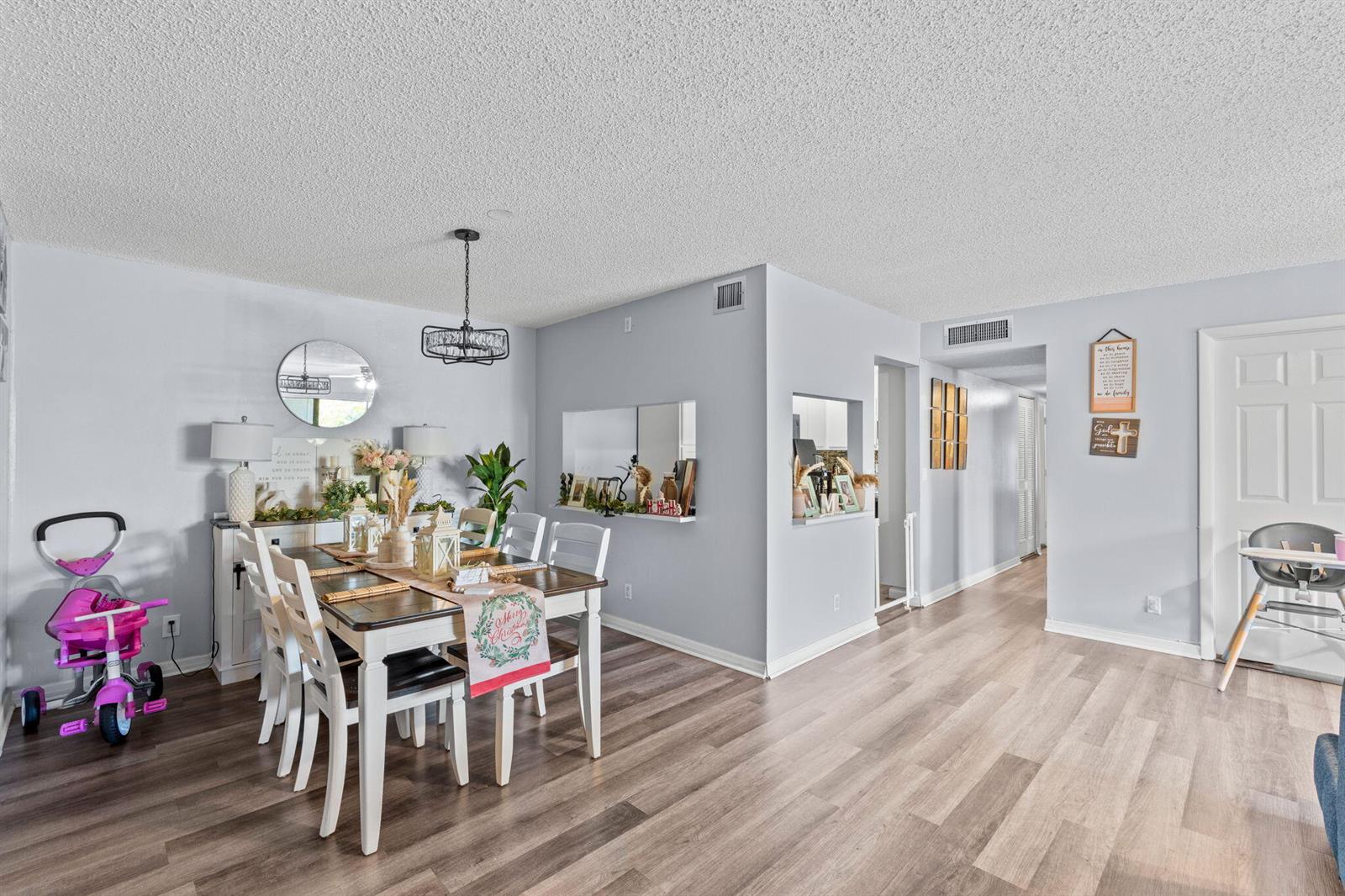 A dining area with a wooden table, white chairs, and light wood-look flooring — 723 Sunny Pine Way # H2, FL 33415, FL