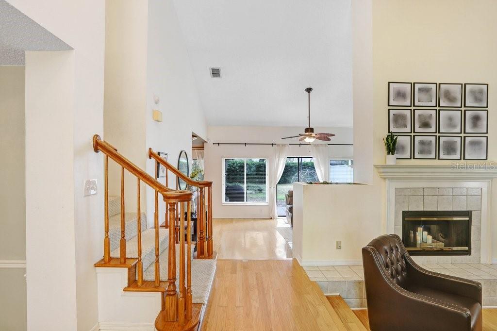 A living room with hardwood floors, a carpeted staircase, and a fireplace with framed art — 6214 FARTHING STREET, TAMPA, FL