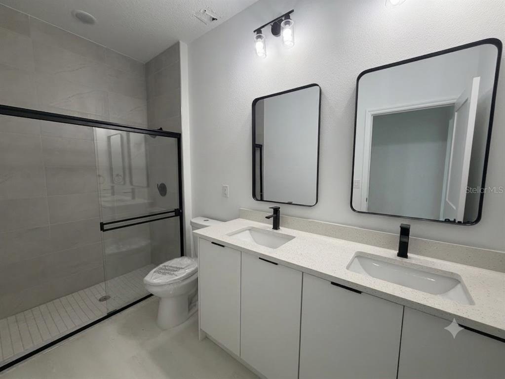 A modern bathroom features a double vanity with black faucets, two mirrors, and a shower — 13542 SW 114TH PLACE, DUNNELLON, FL