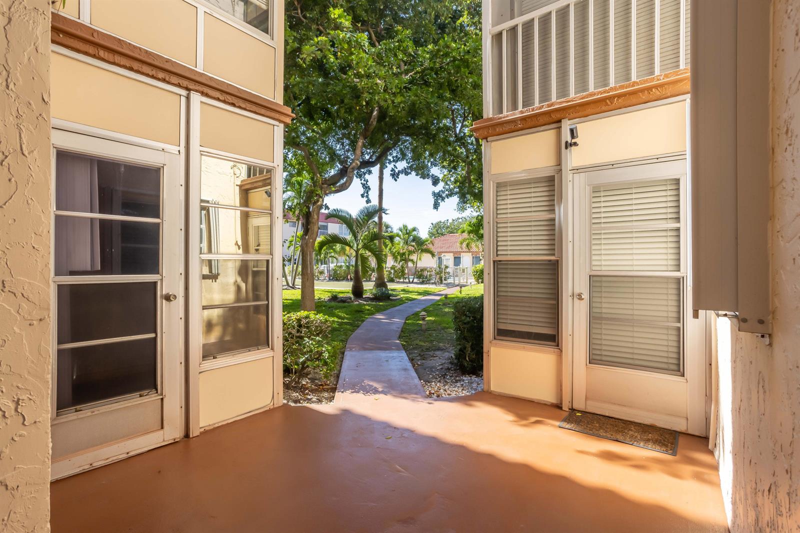 A view from a covered patio looking out toward a landscaped courtyard and walking path — 700 SE 6th Avenue # 107, Deerfield Beach FL 33441, DEERFIELD BEACH, FL
