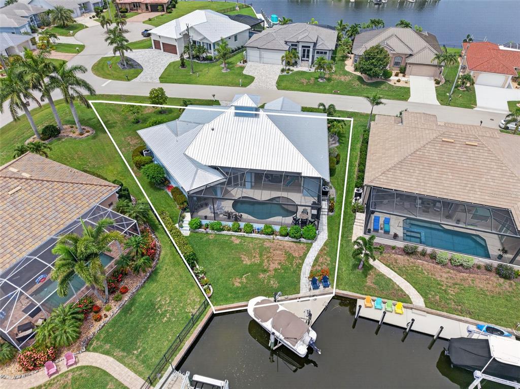 An aerial view shows a house with a pool cage and boat dock on a canal — 3520 ORIOLE DRIVE, PUNTA GORDA, FL