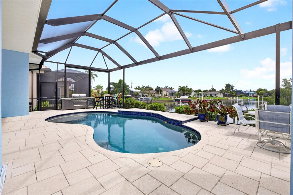 A screened-in patio features a swimming pool, outdoor kitchen, and views of a canal — 3520 ORIOLE DRIVE, PUNTA GORDA, FL