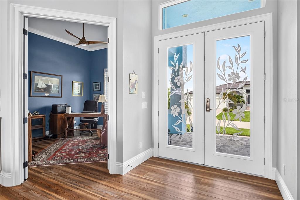 A view of an entryway with wood flooring, a blue office, and double glass-paneled doors — 3520 ORIOLE DRIVE, PUNTA GORDA, FL