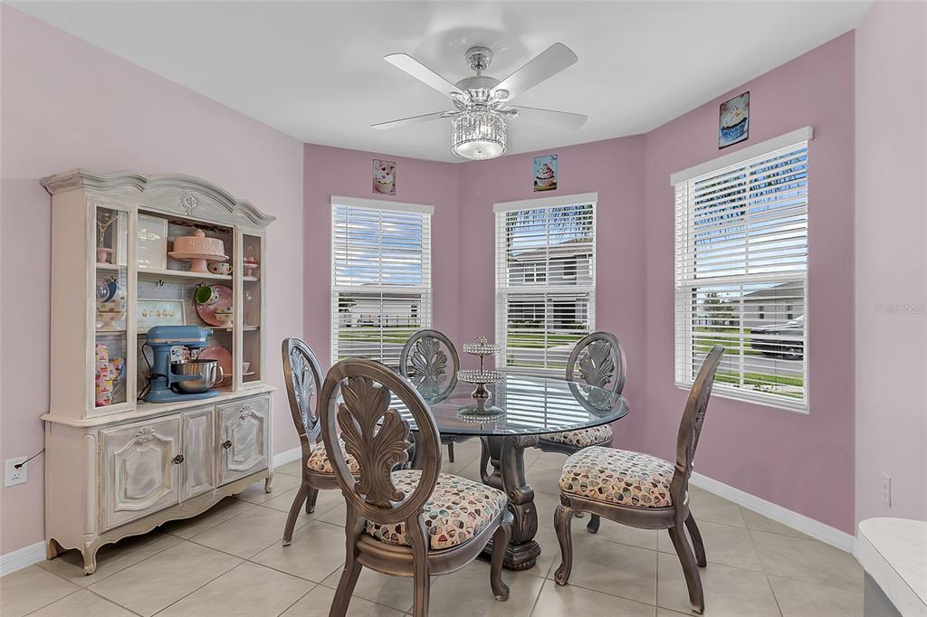A dining room with pink walls, a glass-topped table, four chairs, and a hutch — 3241 CARPENTARIA DRIVE, NEW SMYRNA BEACH, FL