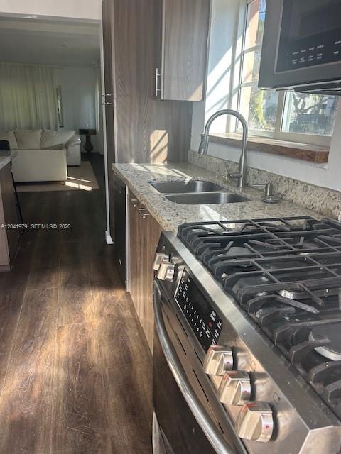 A kitchen with wood cabinets, granite countertops, and a gas range overlooks a living area — 1785 Calais Dr # 5, Miami Beach FL 33141, MIAMI BEACH, FL