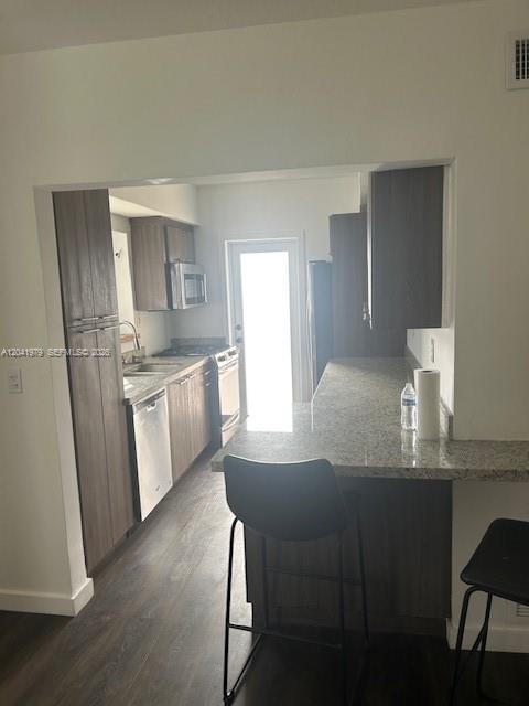 A kitchen features dark wood cabinets, granite countertops, a breakfast bar, and stainless steel appliances — 1785 Calais Dr # 5, Miami Beach FL 33141, MIAMI BEACH, FL