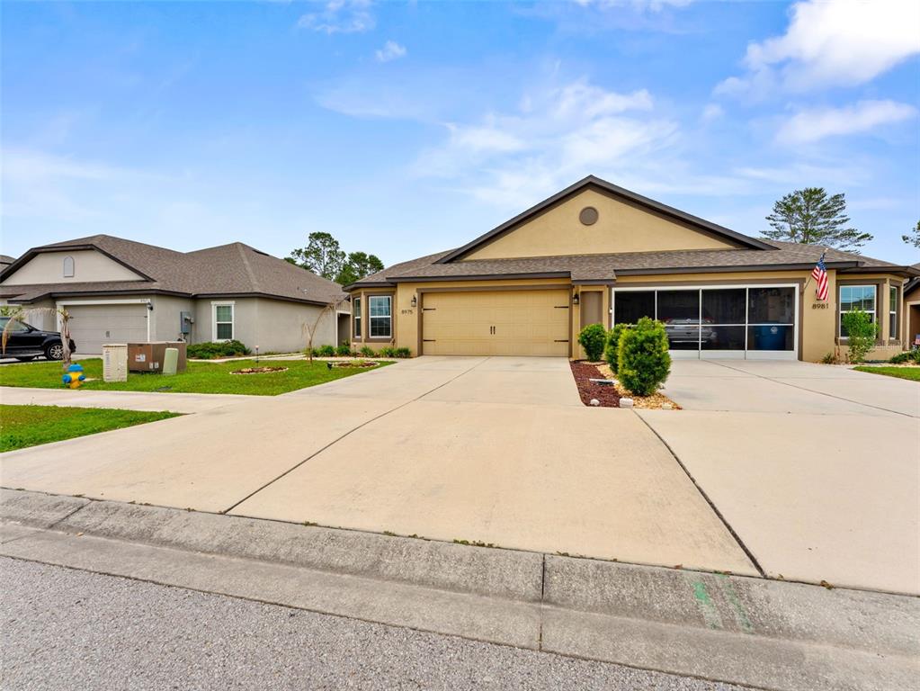 A tan single-story house with a two-car garage and a screened-in front porch — 8975 SOUTHERN CHARM CIRCLE, BROOKSVILLE, FL