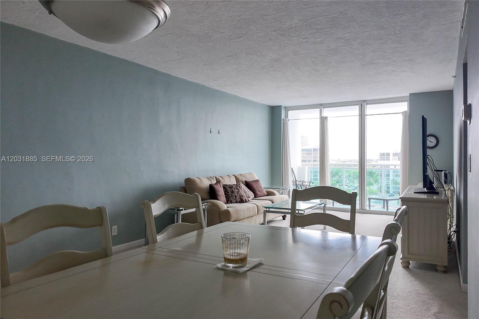 A dining area and living room with light blue walls, beige furniture, and floor-to-ceiling windows — 3000 S Ocean Dr # 712, Hollywood FL 33019, HOLLYWOOD, FL