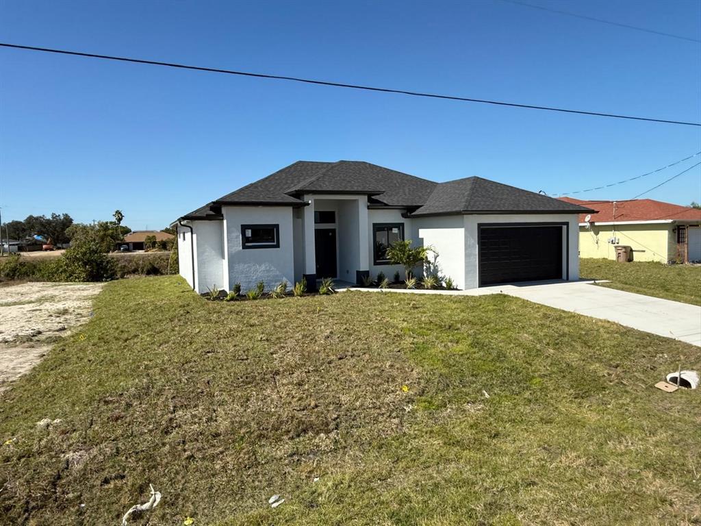 A newly constructed white single-story house with a dark roof and a two-car garage — 1320 NE 14TH AVENUE, CAPE CORAL, FL