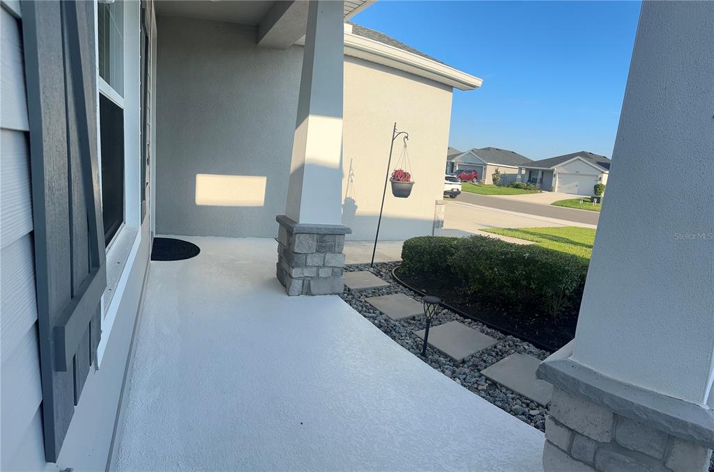 A covered front porch features a white concrete floor, stone-based columns, and a small garden — 16516 66TH LANE E, PARRISH, FL