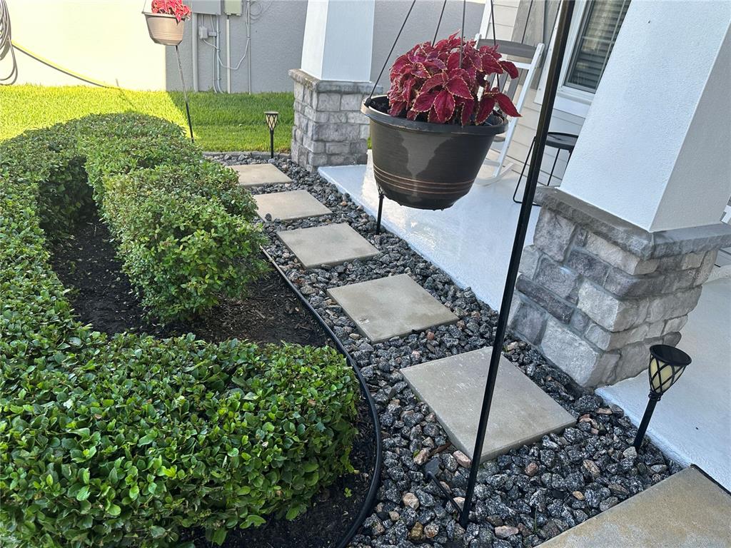 A front porch features a hanging plant, stone-accented columns, and a stone walkway with landscaping — 16516 66TH LANE E, PARRISH, FL
