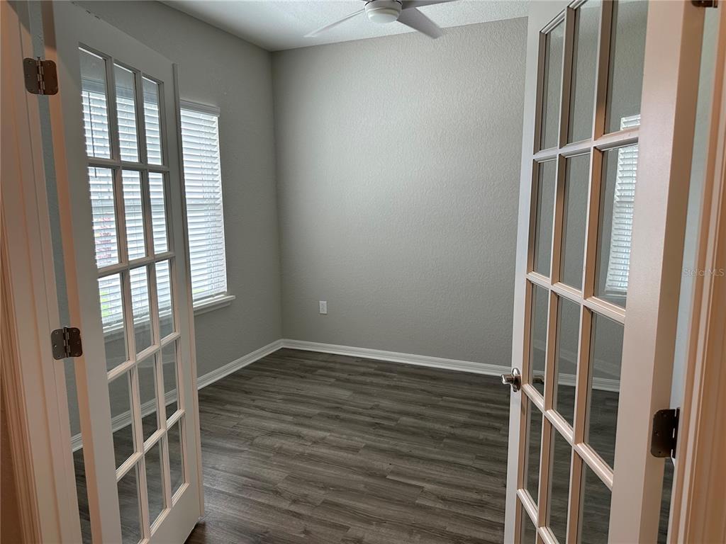 A small room with gray walls, wood-look flooring, and white French doors — 16516 66TH LANE E, PARRISH, FL