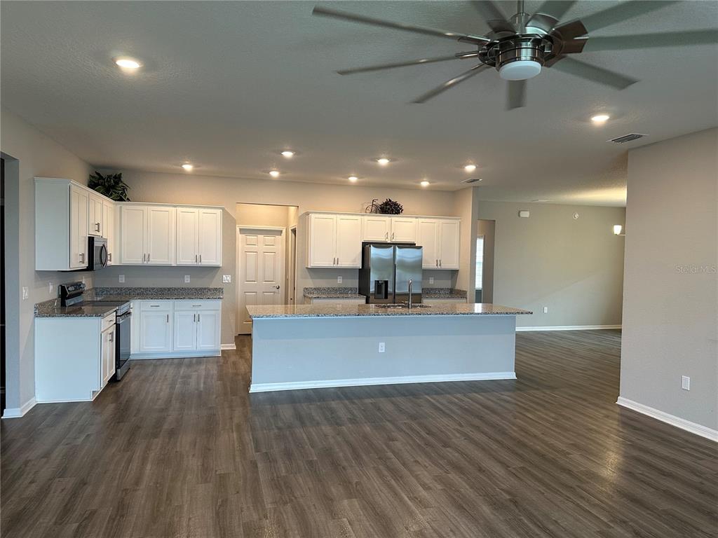 A kitchen with white cabinets, granite countertops, and a large island in an open-concept space — 16516 66TH LANE E, PARRISH, FL