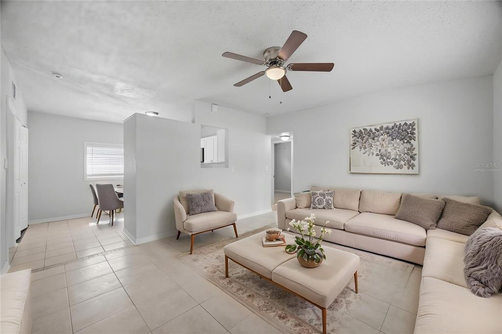 A living room with light tile floors, a beige sectional, and an adjacent dining area — 6629 SIERRA TERRACE, NEW PORT RICHEY, FL