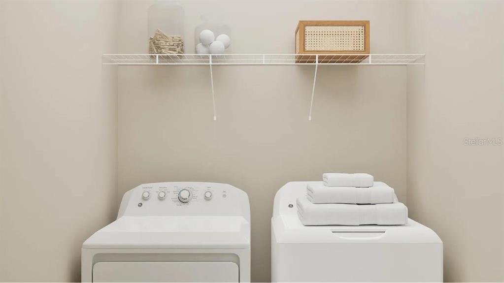 A laundry room features a white washer and dryer beneath a wire storage shelf — 6611 CORAL VISTA DRIVE, RIVERVIEW, FL
