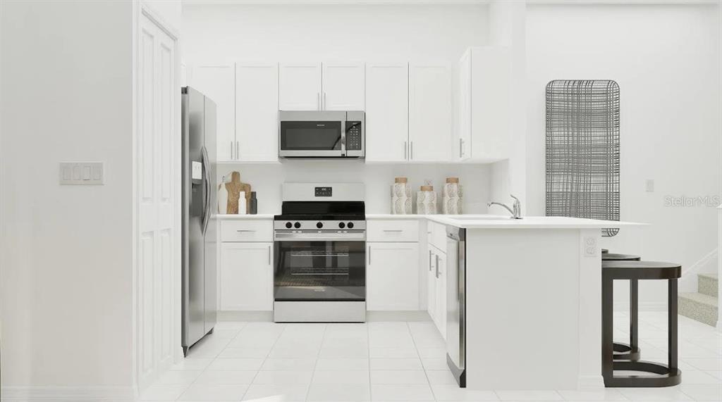 A modern kitchen features white cabinets, stainless steel appliances, and a white island — 6611 CORAL VISTA DRIVE, RIVERVIEW, FL