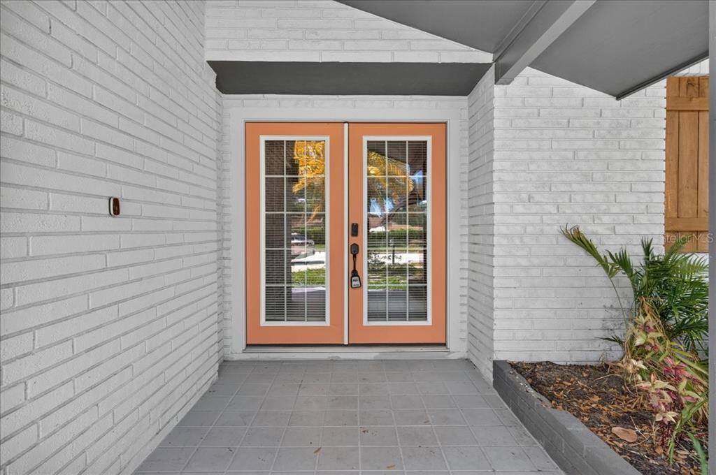 A white brick exterior features a double front door with orange frames and glass panes — 1779 UNION STREET, CLEARWATER, FL