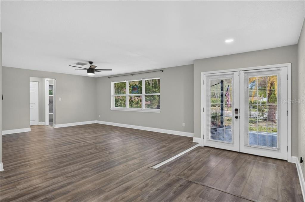 A spacious room with gray walls, wood-look flooring, a ceiling fan, and double glass doors — 1779 UNION STREET, CLEARWATER, FL