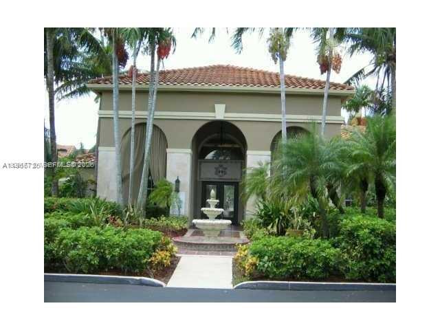 A beige building with a tiled roof features a central fountain and arched entryway — 18330 NW 68th Ave # A, Hialeah FL 33015, HIALEAH, FL