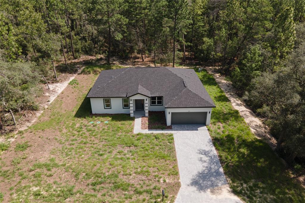 An aerial view shows a single-story house with a dark roof and a paved driveway — 3691 W NORWICK PLACE, DUNNELLON, FL