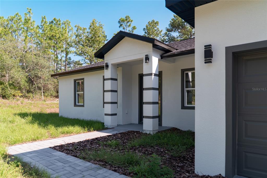 The exterior of a white stucco house features a covered entryway with two decorative columns — 3691 W NORWICK PLACE, DUNNELLON, FL