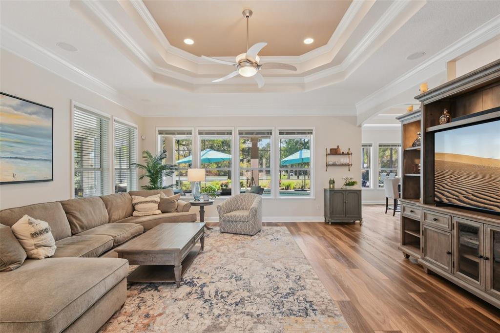 A screened-in pool patio features lounge chairs, two turquoise umbrellas, and a view of water — 101 LONGVIEW WAY N, PALM COAST, FL