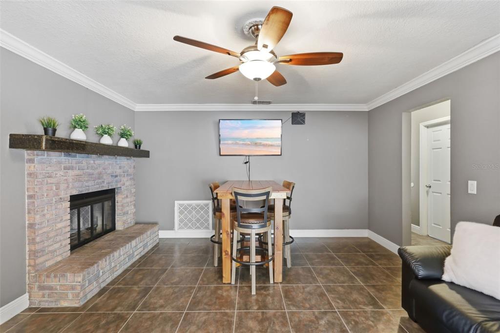 A dining area with a brick fireplace, tile flooring, and a ceiling fan — 8509 SANDBERRY BOULEVARD, ORLANDO, FL