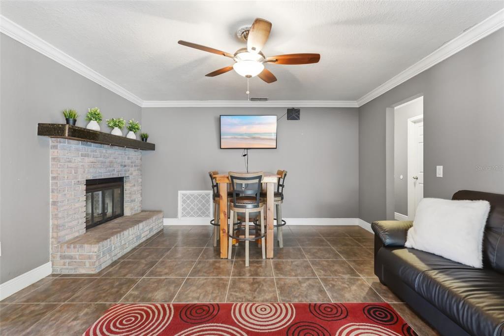 A living room features a brick fireplace, a dining table, and a ceiling fan — 8509 SANDBERRY BOULEVARD, ORLANDO, FL