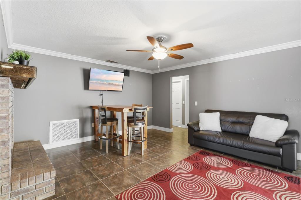 A living room features a dark leather sofa, a dining table, and a brick fireplace — 8509 SANDBERRY BOULEVARD, ORLANDO, FL