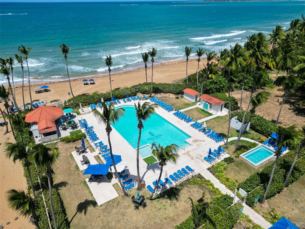 An aerial view shows a swimming pool and lounge chairs near a sandy beach — 3801 RIO MAR VILLAGE, RIO GRANDE, PR