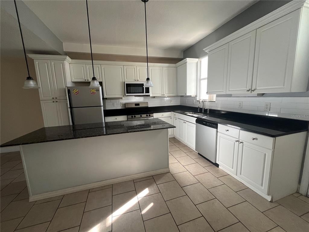 A kitchen features white cabinets, granite countertops, a center island, and stainless steel appliances — 2013 GRAND OAK DRIVE, KISSIMMEE, FL