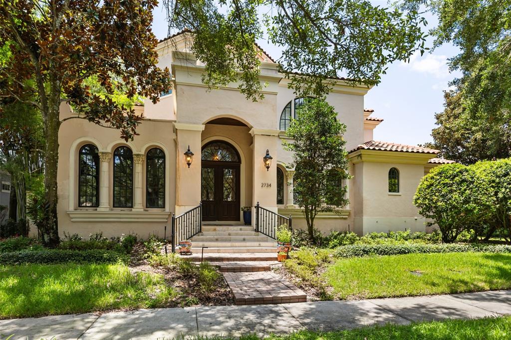 A two-story stucco house with arched windows, a covered entryway, and a brick walkway — 2734 MEETING PLACE, ORLANDO, FL