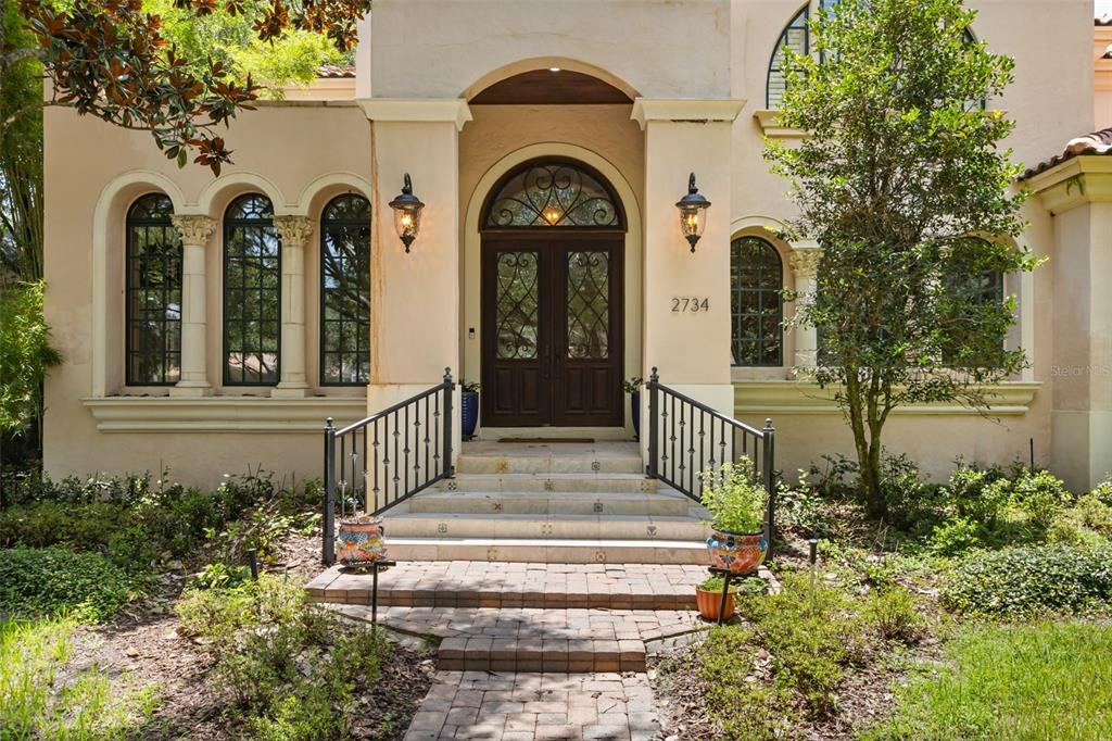 The front entrance of a stucco house features a double door, arched windows, and steps — 2734 MEETING PLACE, ORLANDO, FL